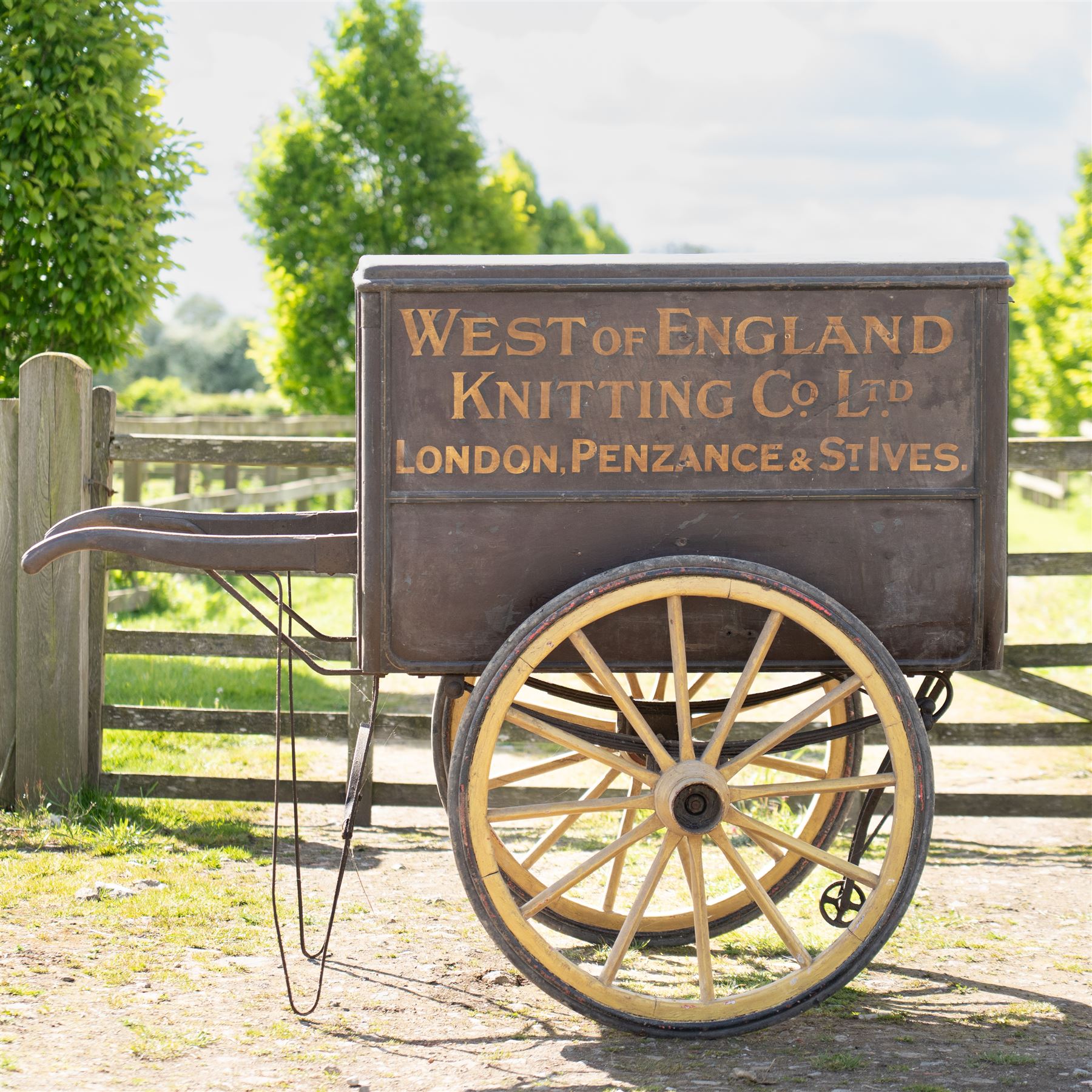 West of England Knitting Co. Ltd. Advertising Hand Cart

A rare and highly decorative late Victorian or Edwardian advertising hand cart, retaining its original black painted finish and gilt signwriting for West of England Knitting Co. Ltd., London, Penzance & St Ives. The enclosed box body is mounted on large cream painted wooden spoked wheels and fitted with rear push handles, allowing the cart to be manoeuvred by hand. Intended as a promotional and delivery vehicle for one of Britain's best known knitwear manufacturers, the cart survives as an evocative piece of commercial advertising history. The interior remains accessible via twin rear doors, while traces of the original maker's transfer for the Warwick Carrier are visible. An unusual and attractive display piece suited to collectors of advertising, transport memorabilia and social history.

Features

• Original hand painted gilt signwriting for West of England Knitting Co. Ltd.
• Advertising panels referencing London, Penzance and St Ives
• Enclosed wooden box body with twin rear access doors
• Original black painted finish with period lettering
• Large cream painted wooden spoked wheels with iron tyres
• Rear push handles for hand propelled operation
• Warwick Carrier maker's transfer remains visible
• Original undercarriage and running gear
• Attractive display piece with strong commercial advertising appeal
• Suitable for museum, retail, interior or collection display

Dimensions:
Overall length: 190 cm
Body length: 125 cm
Overall width: 140 cm
Body width: 100 cm
Height: 150 cm

Wheel Diameter:
Wheels: 92 cm
