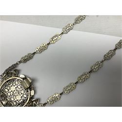 19th century continental silver plated chatelaine, the main body flanked with winged mythical beasts and central soldier slaying a dragon supporting three suspended items to include velvet lined small basket and long clasped filigree chain, together with a thimble