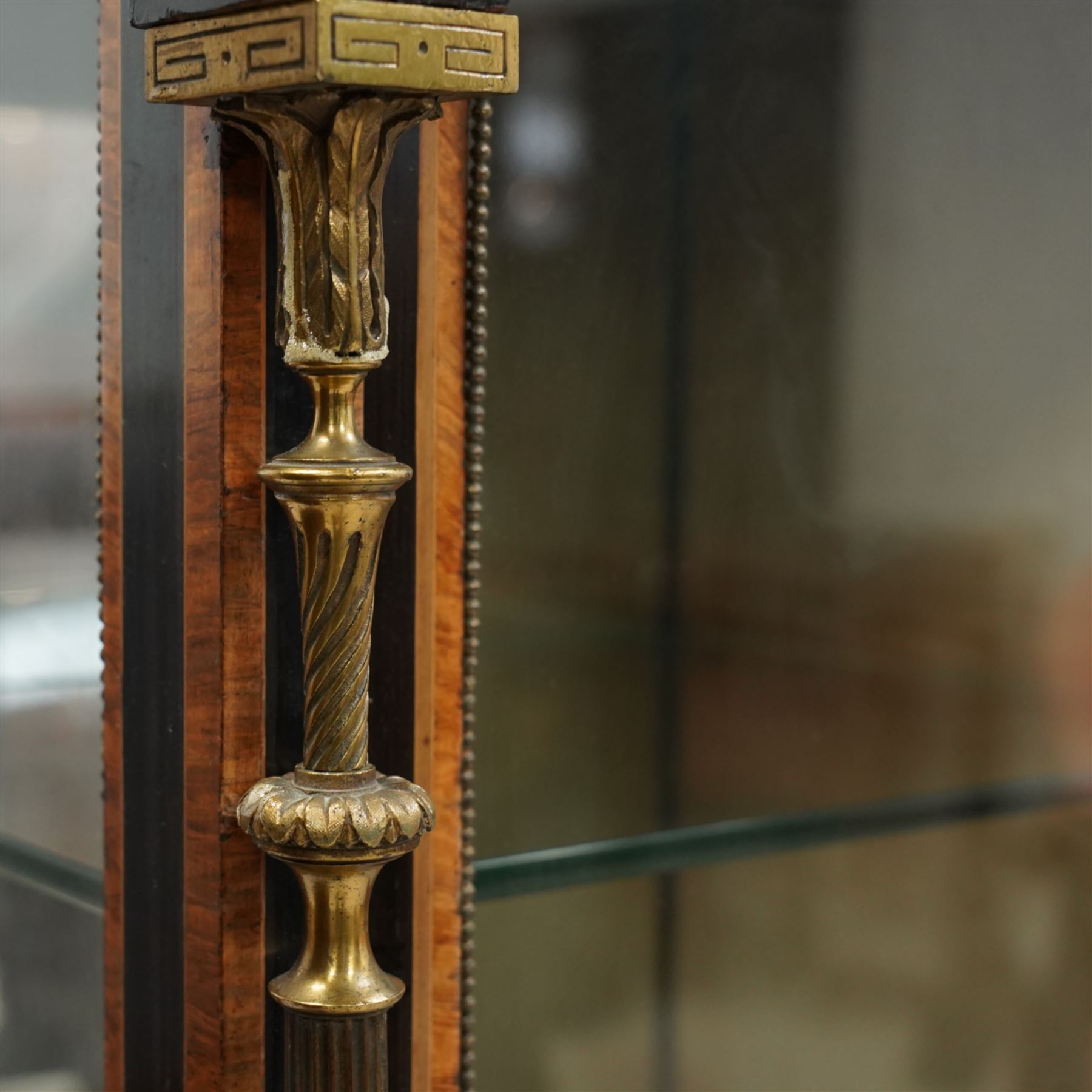 Victorian amboyna and ebonised credenza with glass top, the freeze fitted with two Wedgewood plaques and brass beading above crossbanded arched glazed mirror door flanked by two glazed cabinet doors with two removable glass shelves between four gilt brass reeded floral columns, supported on bun style feet