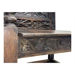Late 19th century Jacobean revival carved oak armchair, the tall back with arched cresting featuring a stylised foliate mask, flanked by carved scrolls, relief carved panel depicting symmetrical foliage, downscrolled arms, on turned front supports united by stretchers