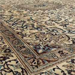 Persian Nain carpet, ivory field with concentric medallion in shades of blue and beige, surrounded by scrolling vines, palmettes and floral sprays, enclosed by multiple borders with intricate foliate motifs, originating from the Nain region of central Iran