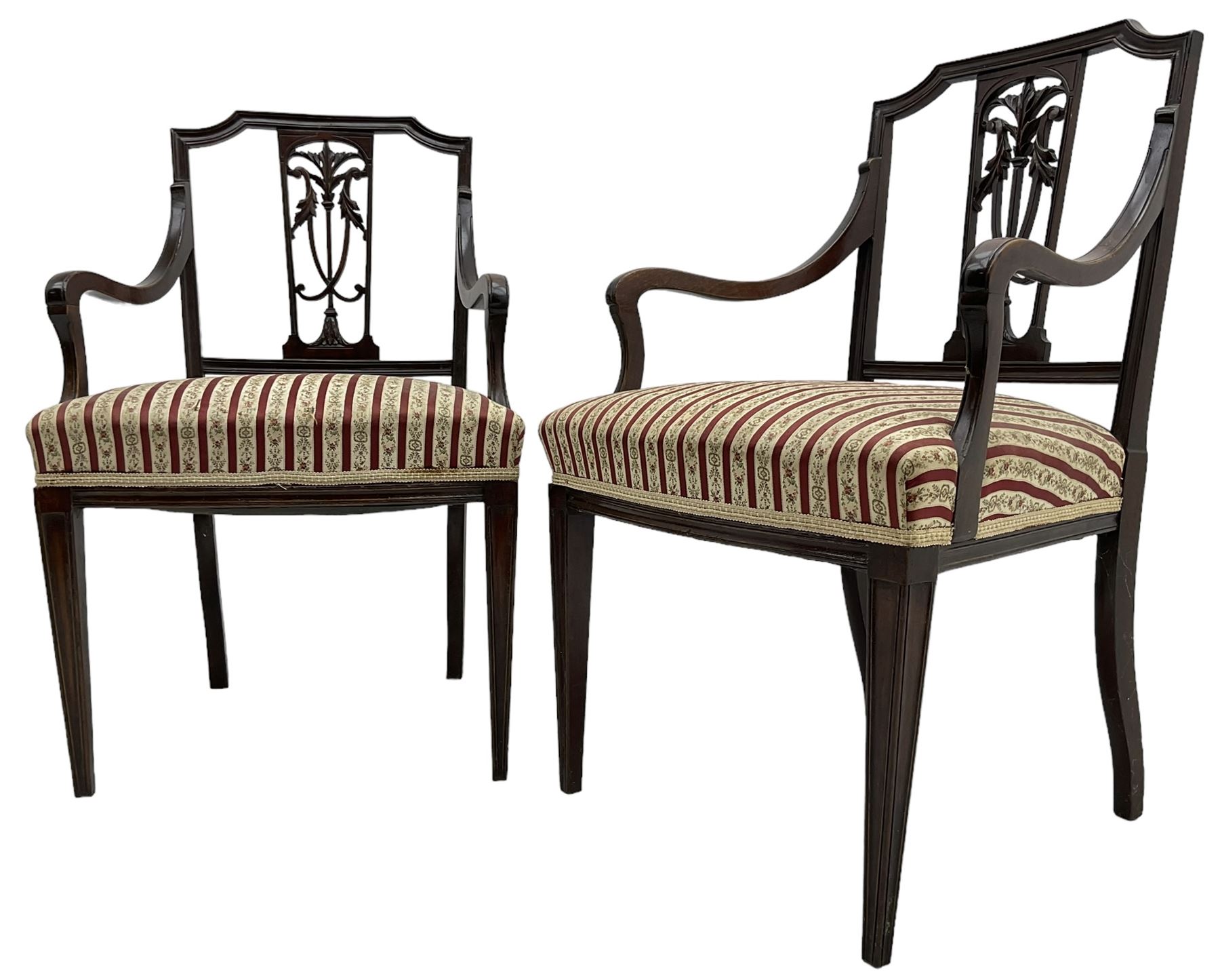 Edwardian mahogany framed three-piece salon suite - two-seat sofa, stepped cresting rail over acanthus and scroll carved pierced splat, upholstered in striped fabric (W124cm, H87cm, D62cm); and a pair of matching armchairs (W60cm) 
