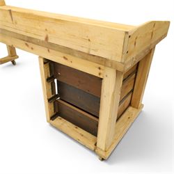Mid-20th century pitch pine and beech bakers table, three quarter galleried rectangular plank top, three drawer pedestal with iron handles and runners, square supports with iron spandrel, raised on castors 