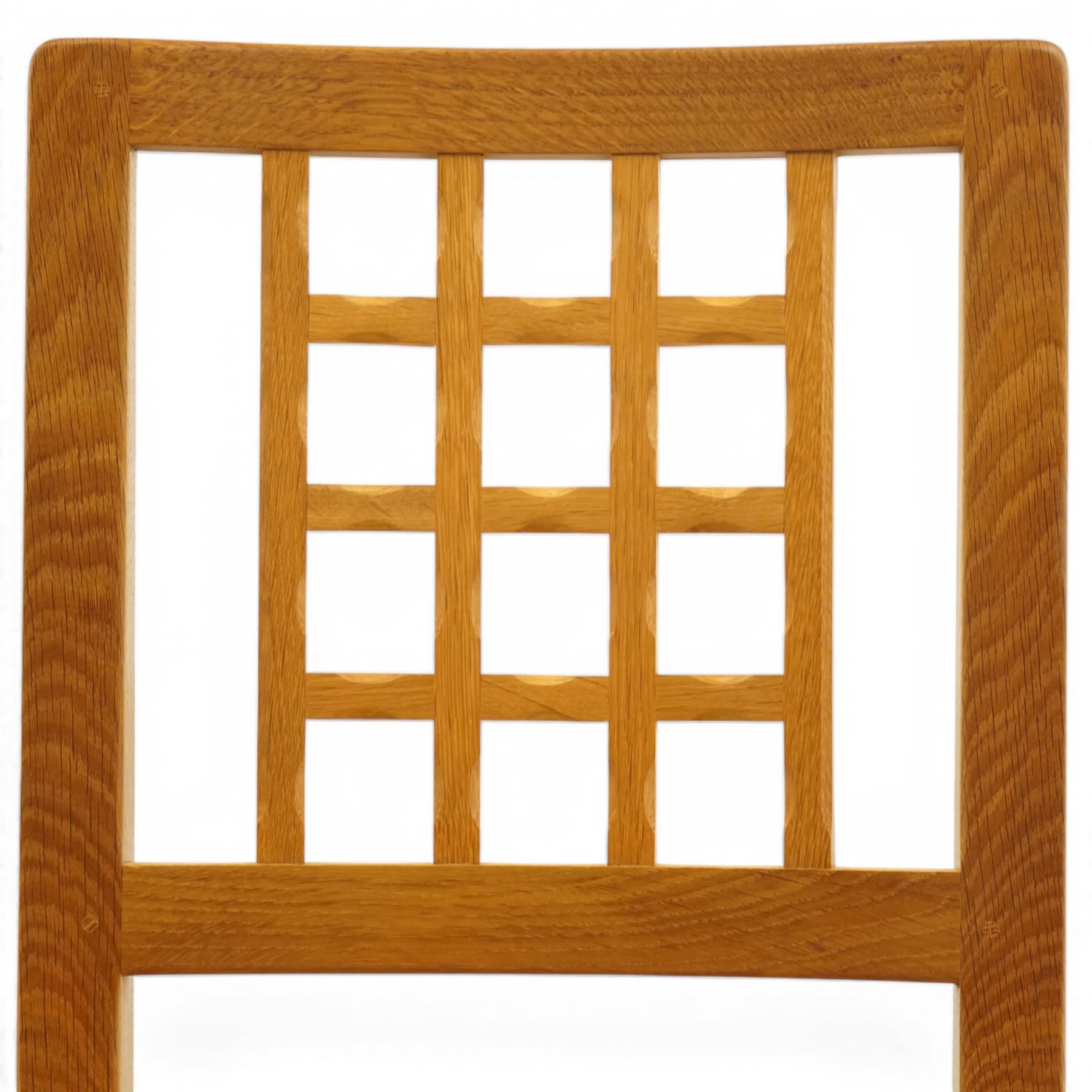 Knightman - eight oak dining chairs, the rectangular back with square section lattice splat enclosed by straight stiles and top rail, drop in upholstered seat in pale patterned fabric, raised on square section legs with chamfered detailing united by stretchers, with carved knight signature, by Horace Knight of Thirsk
