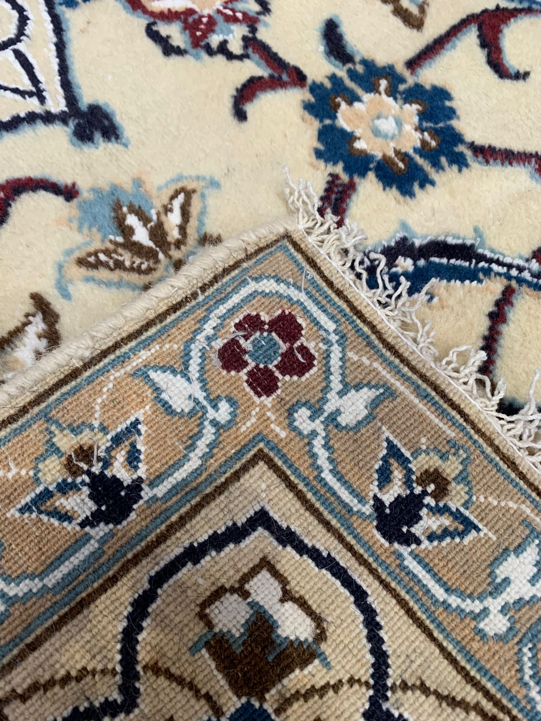 Persian Kashan ivory ground rug, central medallion surrounded by scrolling leafy branches and stylised flowerhead motifs, scrolling border decorated with further stylised plant motifs