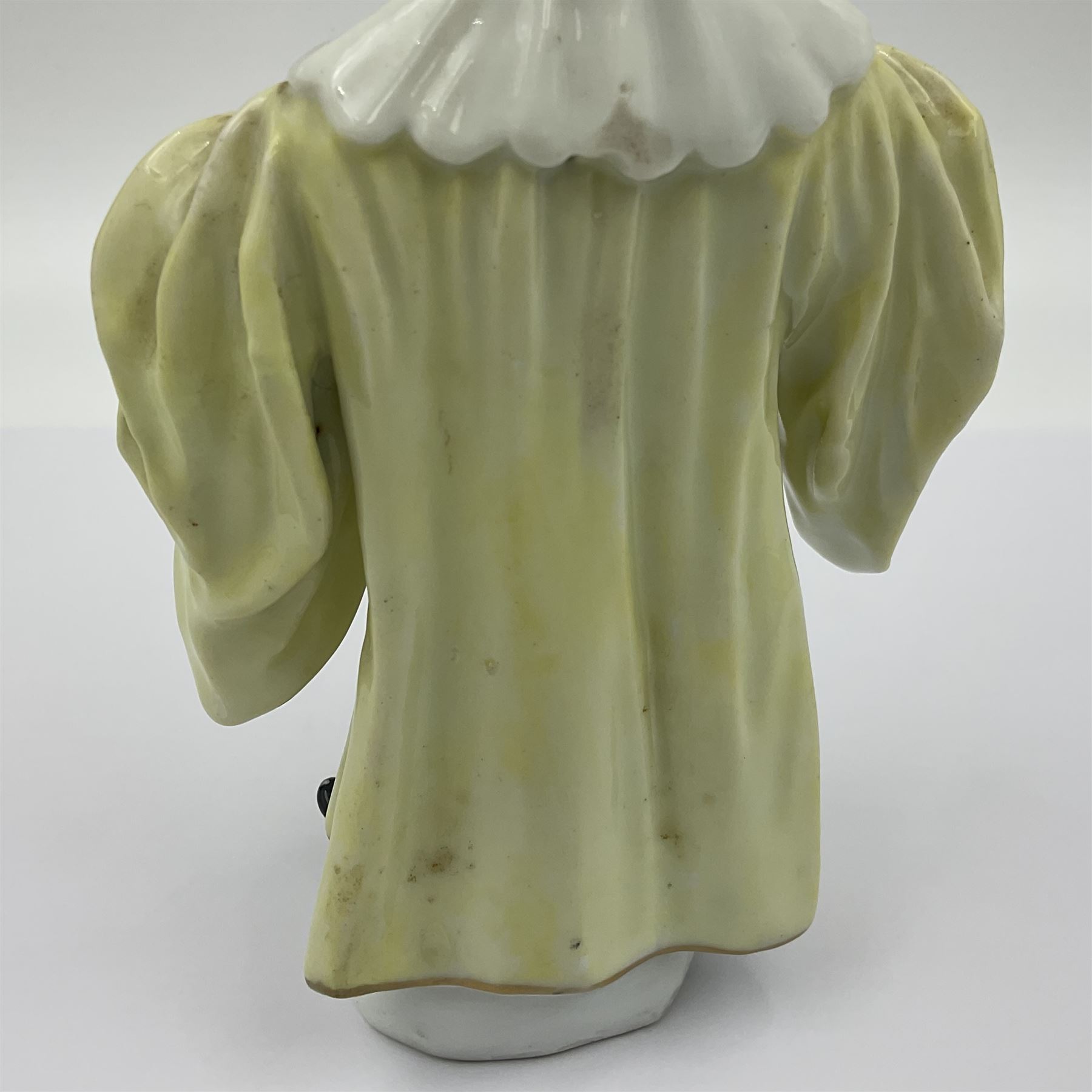 18th century Meissen figure of a Avvocato or the Lawyer from the Commedia Dell'arte series, circa 1740-45, modelled by J J Kandler, wearing gilt edged black tricorn hat, white mask, and yellow cape adorned with red rosettes, holding a scroll in his right hand, upon shaped oval base, no visible mark, H14.5cm