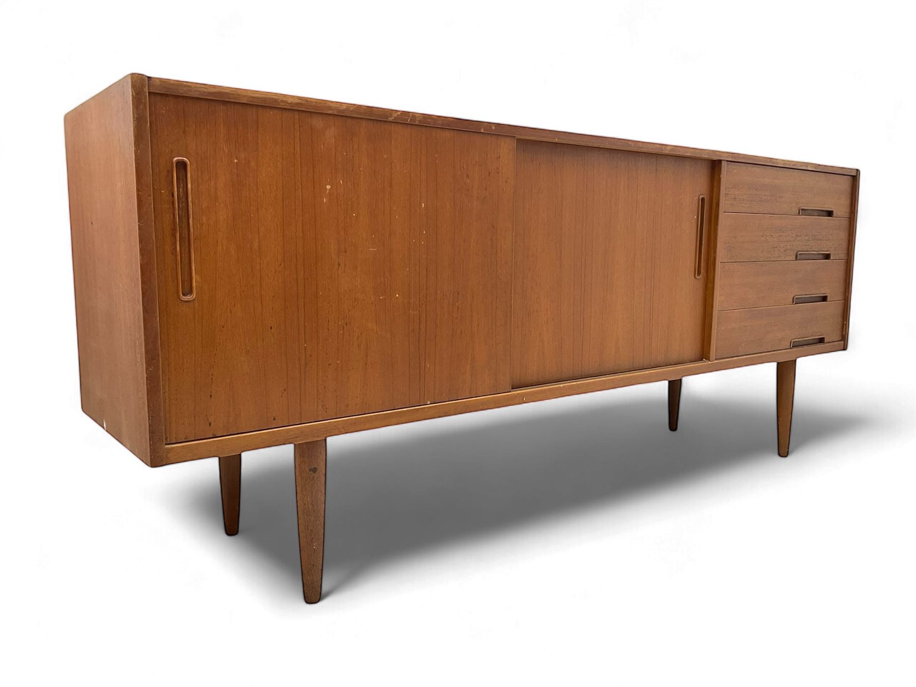 Nils Jonsson - mid-20th century teak sideboard, rectangular top over three-section base, left and centre sections with sliding double doors enclosing shelving, right section with four drawers, raised on tapered supports