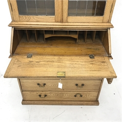 Early 20th Century light oak bureau bookcase, two lead glazed doors, three adjustable shelves above fall front enclosing fitted interior, four short and two long drawers, platform base, W101cm, H213cm, D54cm