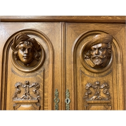 Late 19th century Flemish oak dresser, projecting cornice over two arched panelled doors with carved busts and relief carved ribbons and leafage, two fluted and acanthus carved supports with carved jester figures, central winged maiden support, moulded rectangular lozenge pattern top, three gadroon carved drawers above three panelled doors, the centre door carved with scrolled foliage and urn, stepped moulded plinth, turned and carved feet, W161cm, H227cm, D61cm