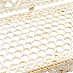 Victorian revival heavy cast iron garden bench, ornate back rest with scrolls, floral motifs and central crest, pierced lattice seat, curved arms and decorative legs, painted in antique white, in the Gothic Coalbrookdale style