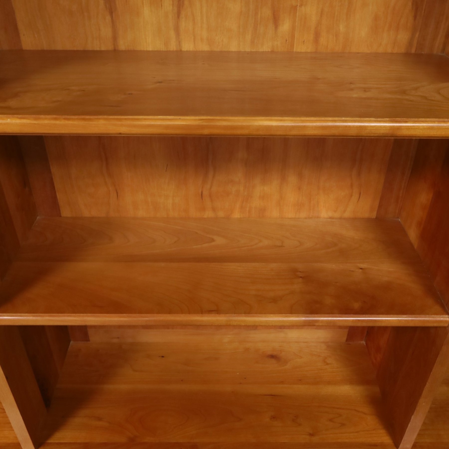 Philip Koomen (1953-) - Craftsman-made modern cherrywood large open
bookcase with a cupboard base, upper section with a
shaped cornice above three sections with two open
shelves, the lower section has three cupboards,
each with two panelled doors enclosing a single
shelf, raised on a plinth base