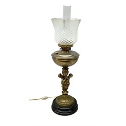 Late 19th/early 20th century brass oil lamp, the central column modelled with two cherubs, supporting the reservoir with frilled glass shade, raised upon circular base, H71cm