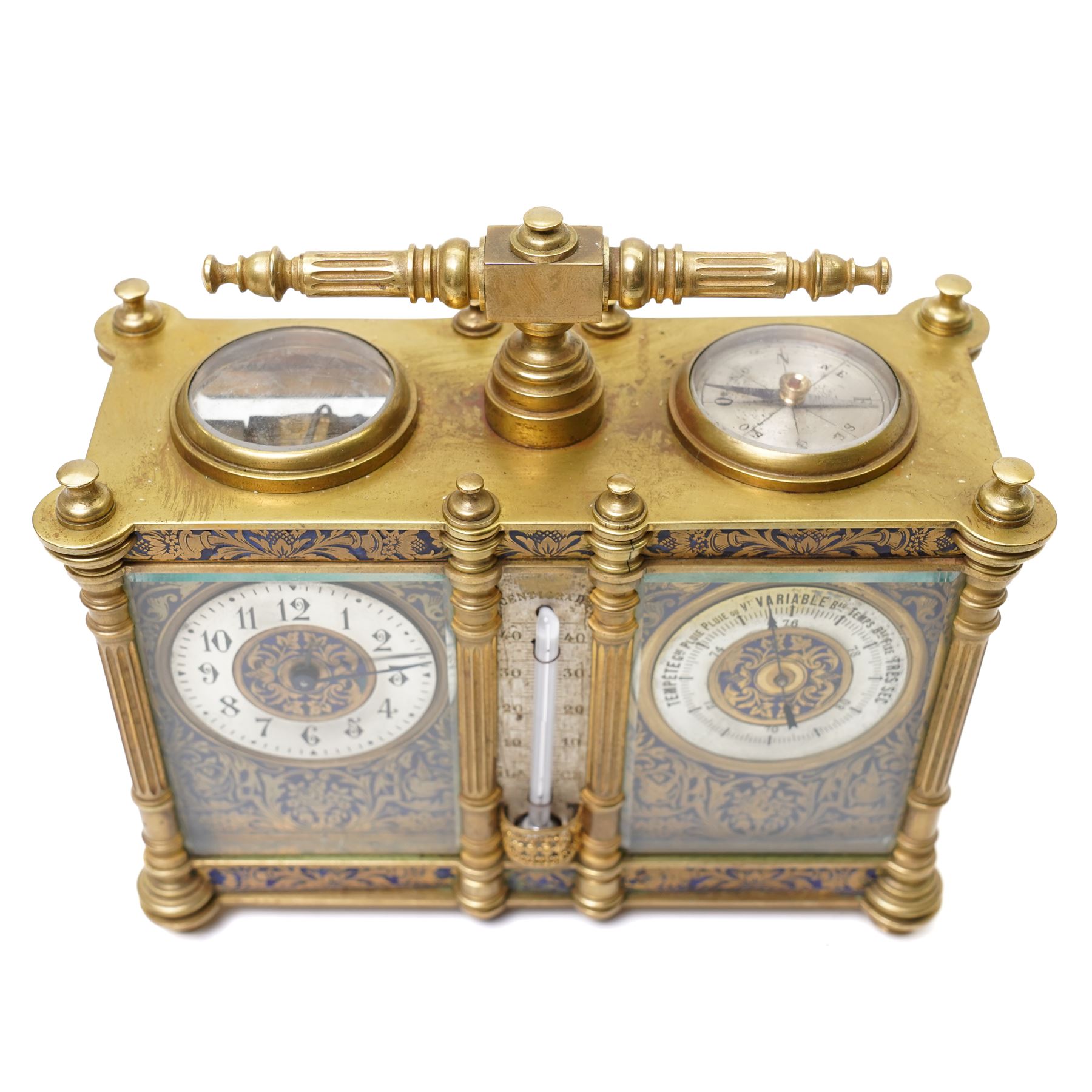 French-late 19th century combination brass carriage timepiece with barometer, thermometer and compass, with a fluted T bar handle and eight matching columns with turned finials, bands of fretted brass to the base and cornice and conforming decoration to the dial masks and dial centres, with silvered chapters to the time dial and barometer and a mercury thermometer between, the top with a circular bevelled viewing glass to the escapement and compass to the other, with a single train 8-day movement and cylinder platform escapement.  With key.