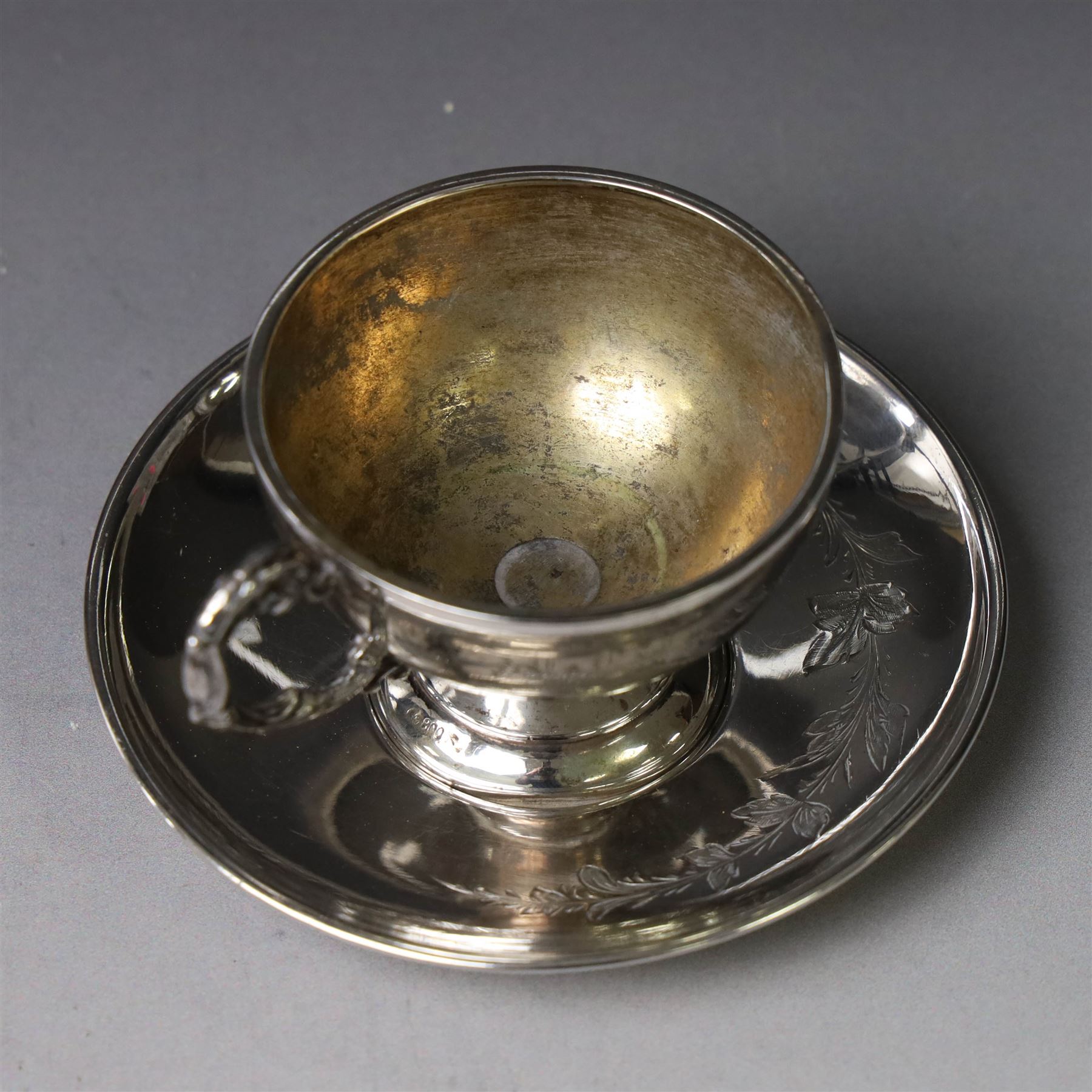 German silver cup and saucer, both with engraved foliate decoration, stamped 800, the saucer with crescent and crown mark