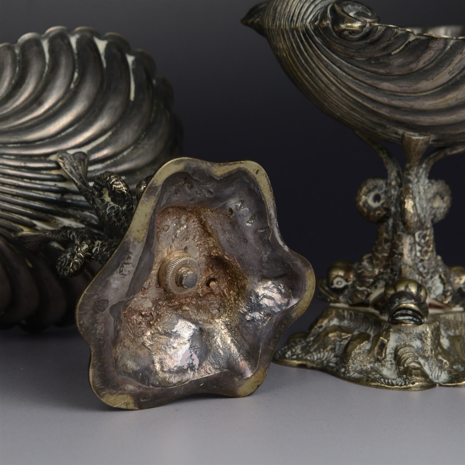 Pair of Victorian silver plated comports, with clam shell bowls supported by three dolphins upon a rocky base, H12cm