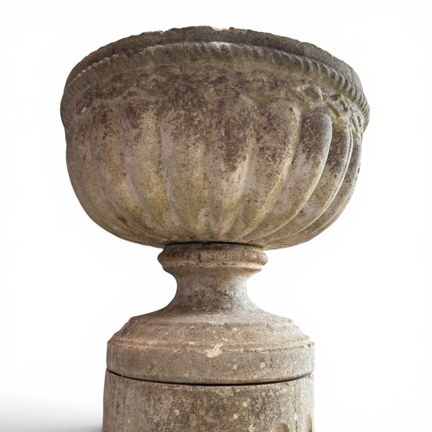 20th century good quality weathered cast stone pedestal urn of ecclesiastical design, circular lobed bowl with rope twist and lattice border, raised on squat base with fluted column  and acanthus decorated base