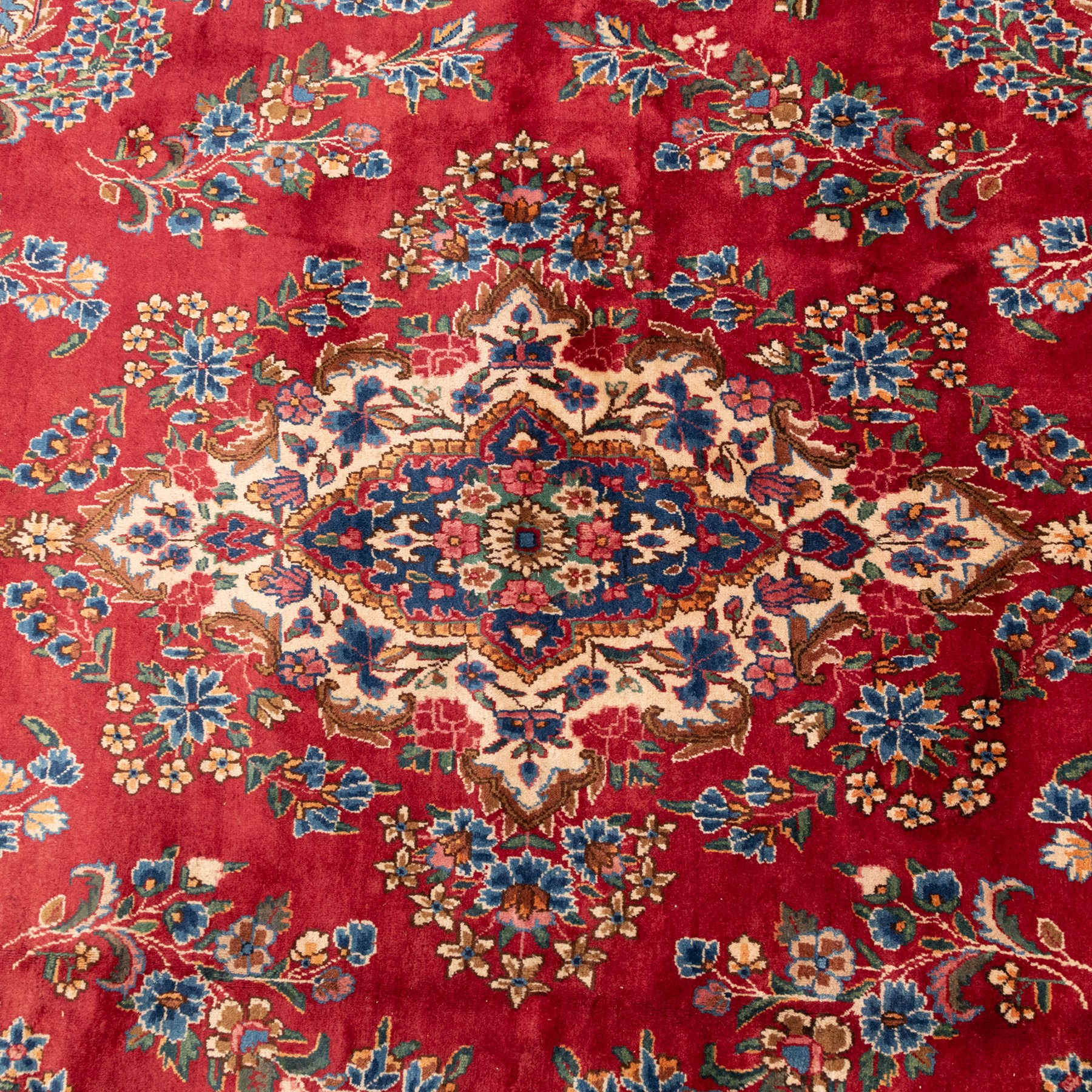 Fine Persian crimson ground Kashan carpet, the busy field with a central floral pole medallion surrounded by bouquets of flowerheads and trailing foliage, the shaped cyan spandrels similarly woven, enclosed by a wide foliate guard band of stylised palmettes and floral designs