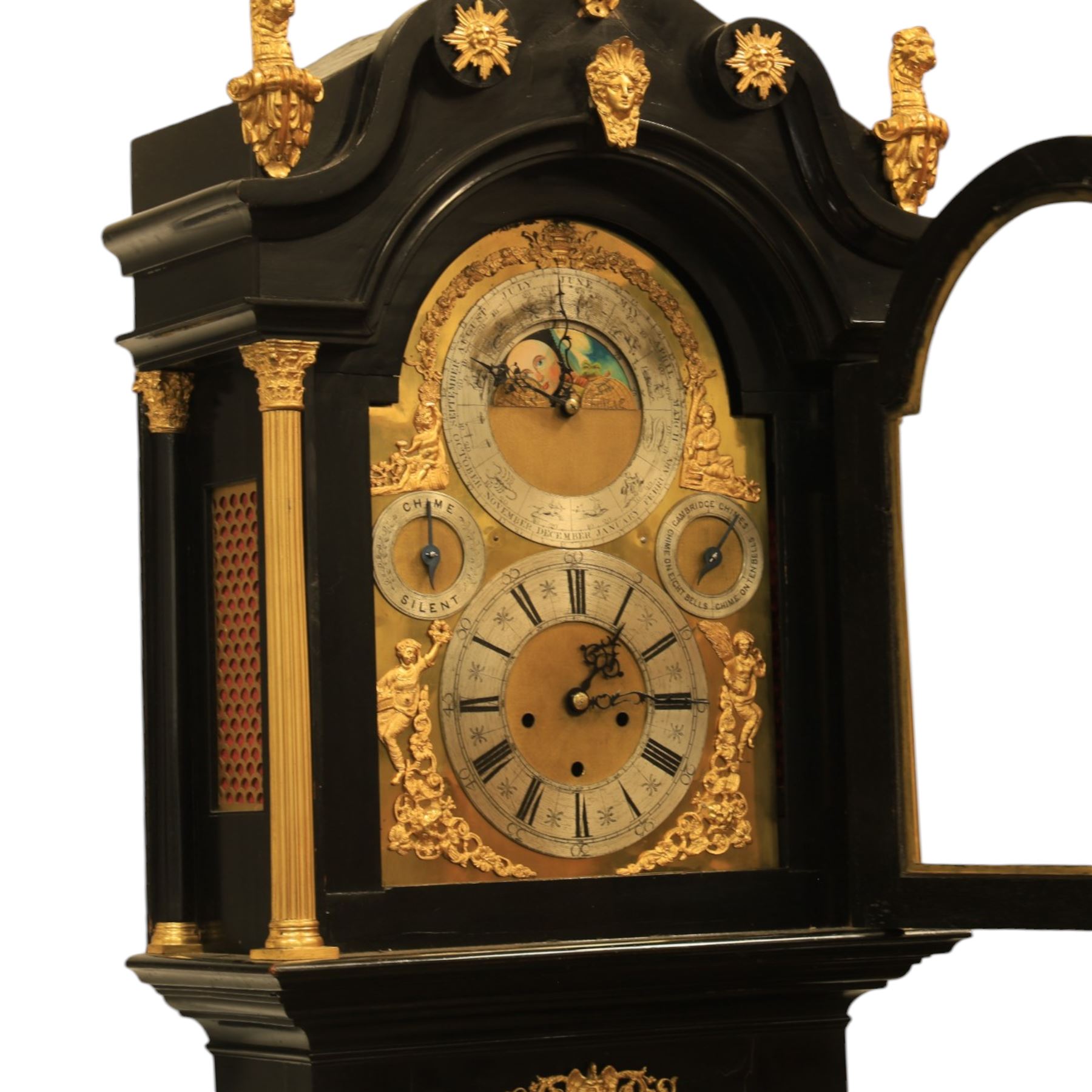 Late nineteenth century ebonised and gilt-bronze mounted musical longcase clock of impressive architectural form, the case of ebonised finish with applied gilt bronze neoclassical inspired masks and mounts, hood of arched form with glazed door, flanked by free fluted columns with gilt bronze Corinthian capitals surmounted by stylized Lion finials, frieze and arch enriched with applied foliate mounts, trunk with a rectangular glazed door bordered by mouldings and flanked by engaged columns with gilt bronze mounts above a shaped projecting base panel with applied central female mask and corner foliate ornamentation, arched brass dial, with a silvered chapter ring and applied cast gilt bronze spandrels and arch decoration, incorporating subsidiary selection dials for chime/silent and tune regulation, offering Cambridge chimes on eight bells and an additional chime sequence on ten bells, brass arch is further embellished with a moon phase aperture with lunar calendar scale, Zodiac symbols, month and date indication on a silvered dial, substantial eight-day, three-train movement with pinned cylinder musical train and a graduated nest of eleven bells with eleven hammers, quarter chiming with separate hour/half-hour strike and chime repetition, movement is regulated by an anchor escapement, with brass disc pendulum, three brass weights, two winding keys and case door key