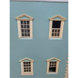 Two modern three storey dolls houses, each painted green with decorated interiors, both upon a single white wooden base, together with a large collection of dolls house furniture, accessories and figures 