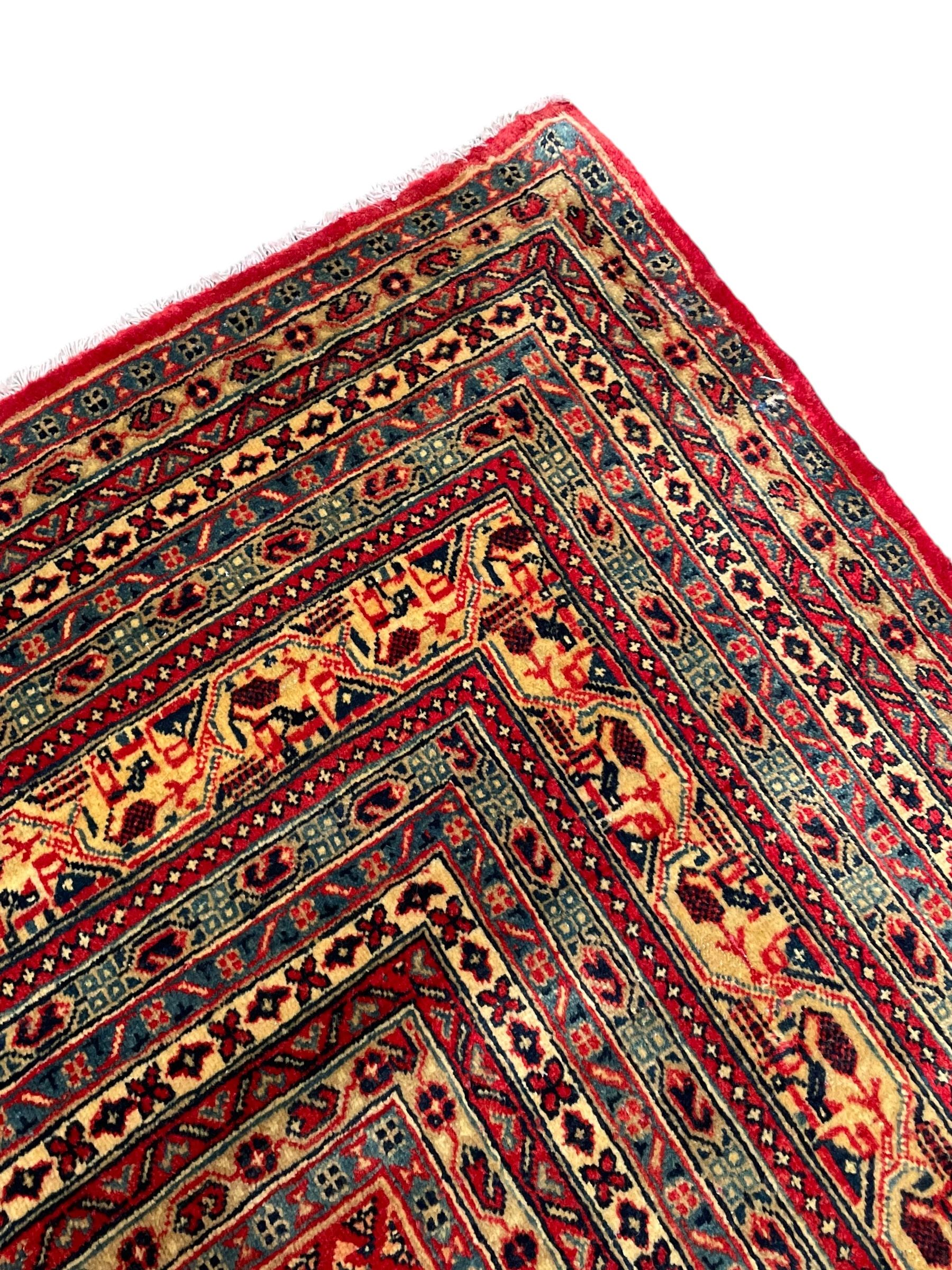 Persian Arak crimson ground carpet, the field decorated profusely with small repeating Boteh motifs, enclosed by multiple border bands decorated with repeating geometric and hook motifs