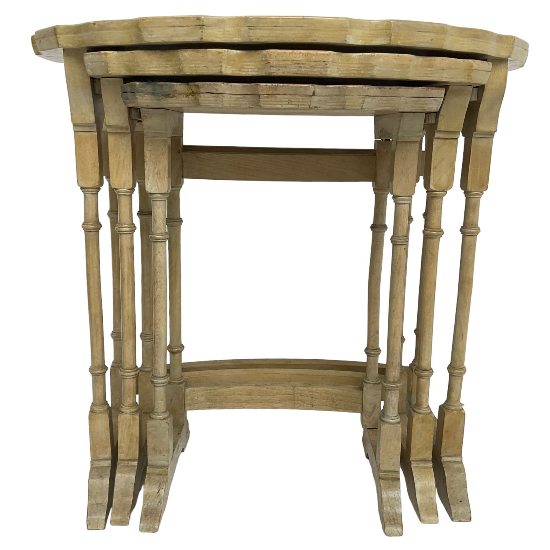 Mid 20th century bleached walnut nest of three tables, oval piecrust tops on turned supports