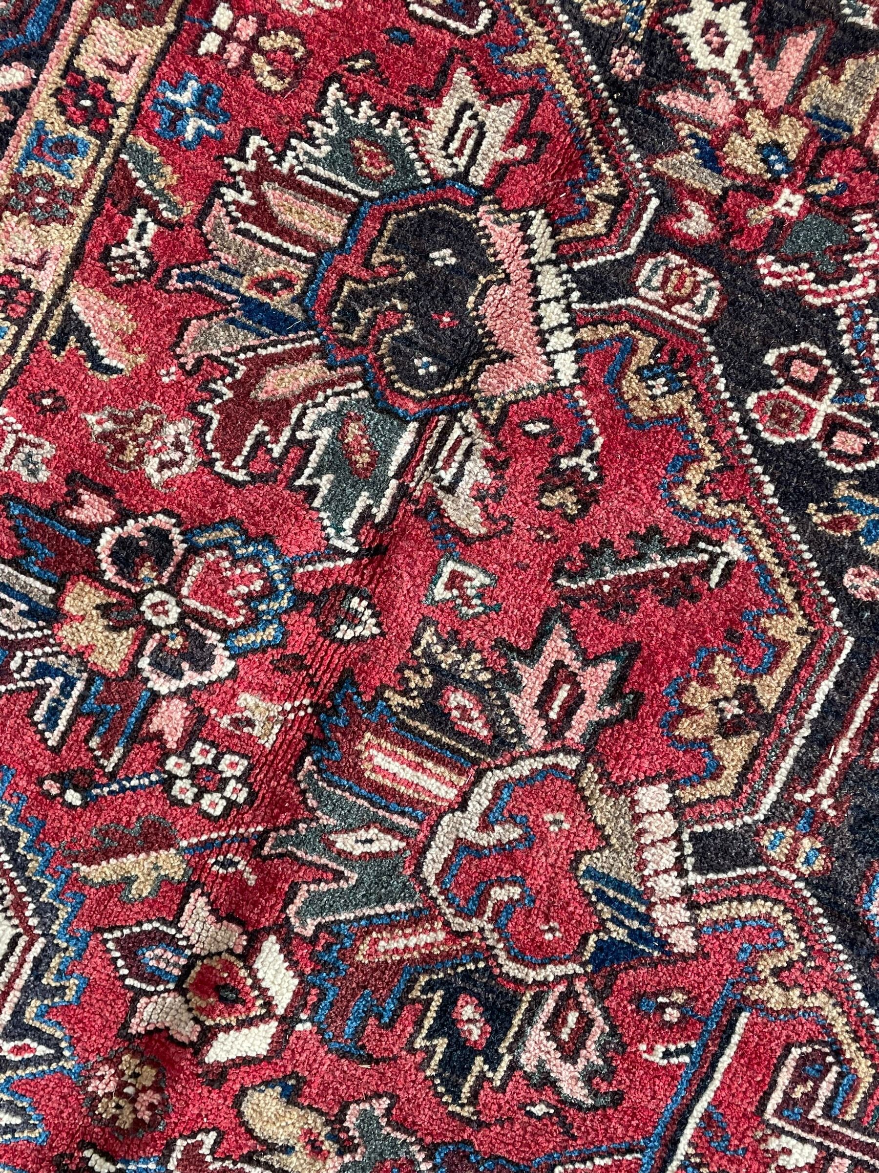Persian Heriz red ground rug, large medallion decorated with palmettes and Ejder motifs, the border decorated with stylised plant motifs, within floral design guard stripes 