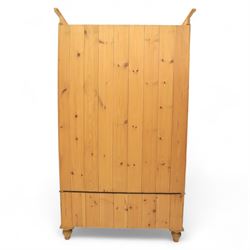 Two contemporary traditional-style wardrobes, projecting plain cornice above two arched moulded panel doors, above a full-width drawer fitted with turned wooden handles, raised on turned bun feet