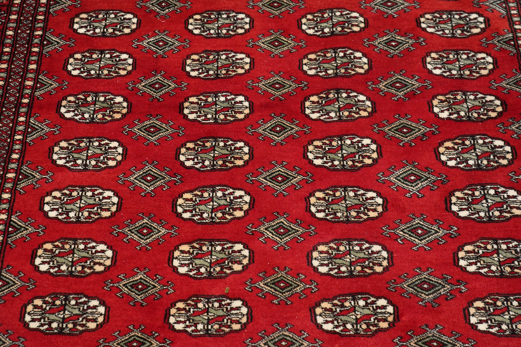 Two Afghan Bokhara crimson ground rugs, the fields decorated with repeating Gul motifs with geometric guard bands (126x190 & 157x250)