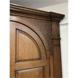 Large George III oak corner cupboard, projecting cornice over two stepped arch doors with fielded panels and blind fret work spandrels, flanked by fluted uprights, cupboard below enclosed by two fielded panel doors, the painted interior fitted with shaped shelves
 