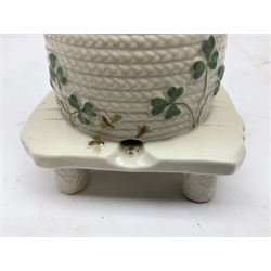 20th century Belleek beehive honey pot and cover, in the form of a bee skep raised on three legs, with black printed mark beneath 
