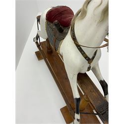 Victorian white finished rocking horse, complete with studded saddle and bridle, brass stirrups and rockers, raised on two turned columns and floor stretcher 