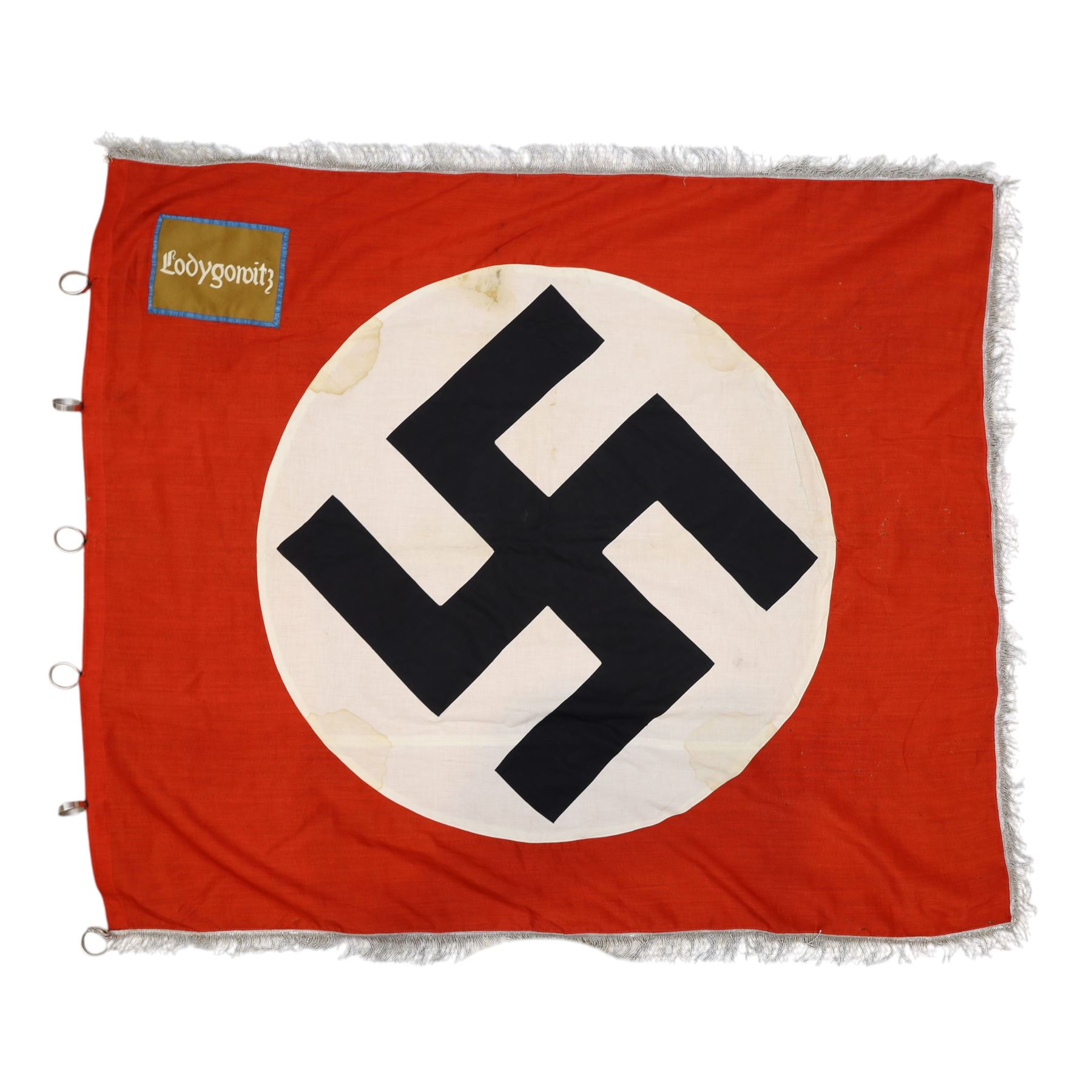 German Third Reich NSDAP flag, with central swastika, blue edged brown panel to the corner with “Łodygowice” embroidered in white, later silver tress added to the edge