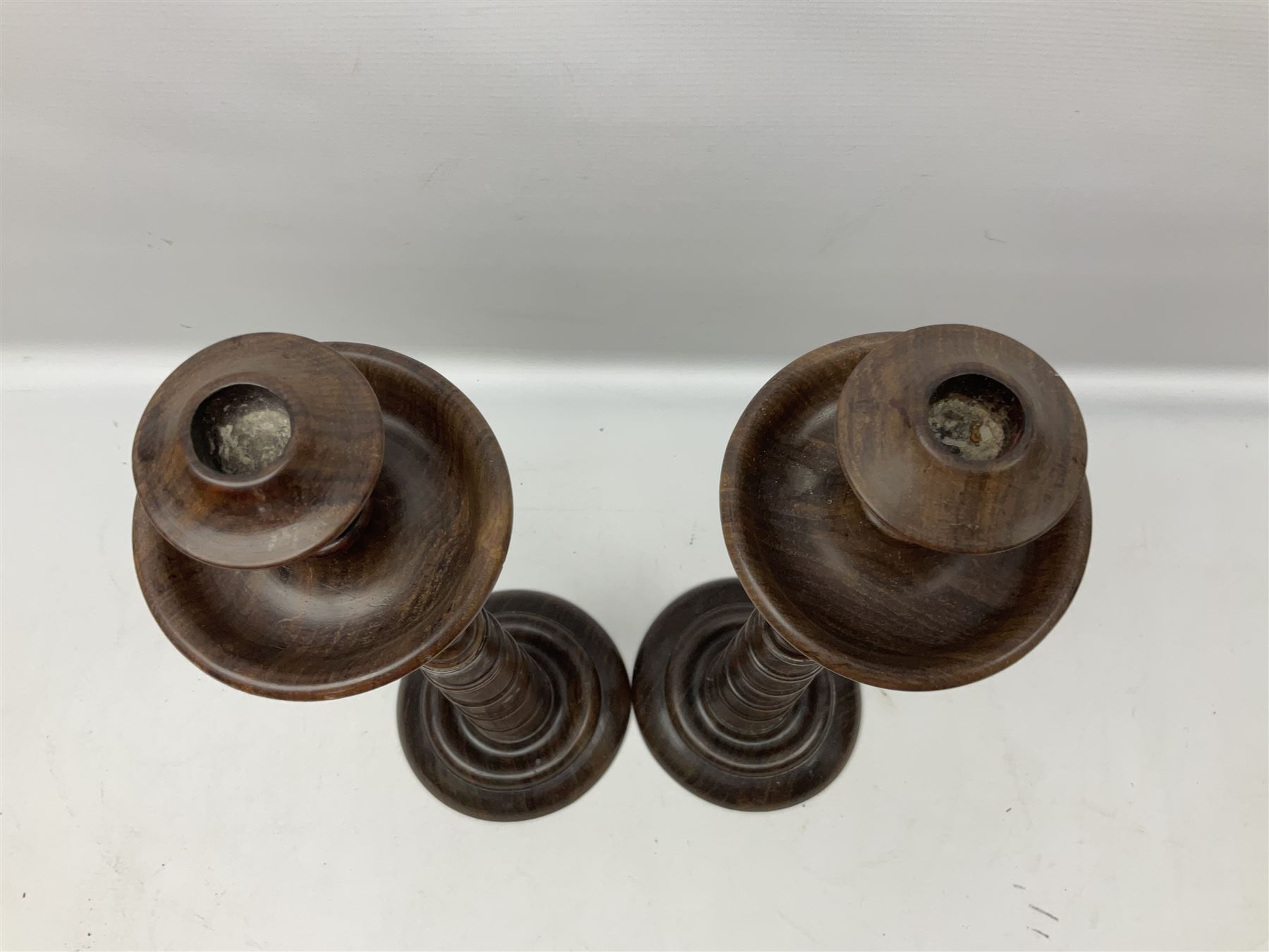 Pair of turned wooden candlesticks, the central column of stepped form raised upon circular spreading base, with drip trays, H56cm