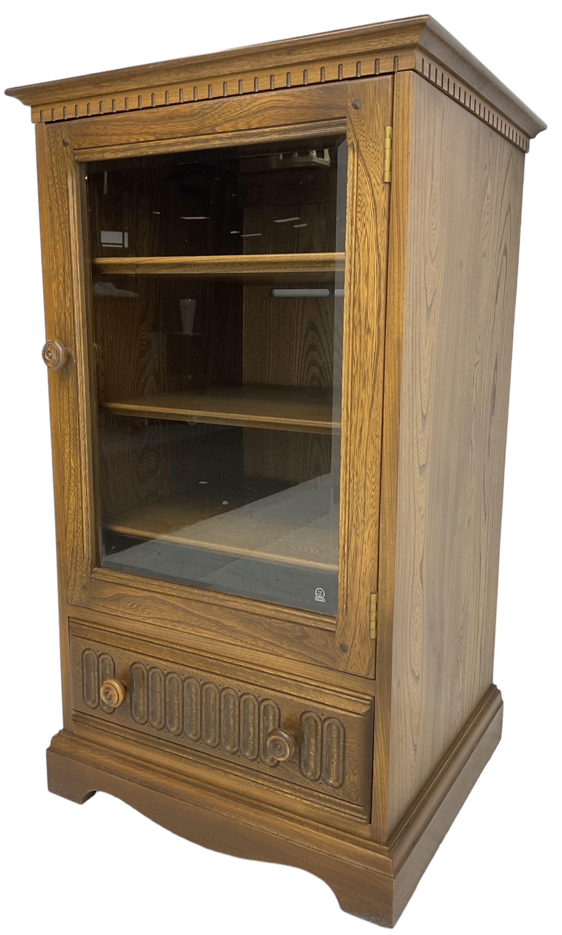 Ercol - mid-20th century dark elm 'Old Colonial' music cabinet, single glazed door enclosing three shelves, single drawer fitted to base