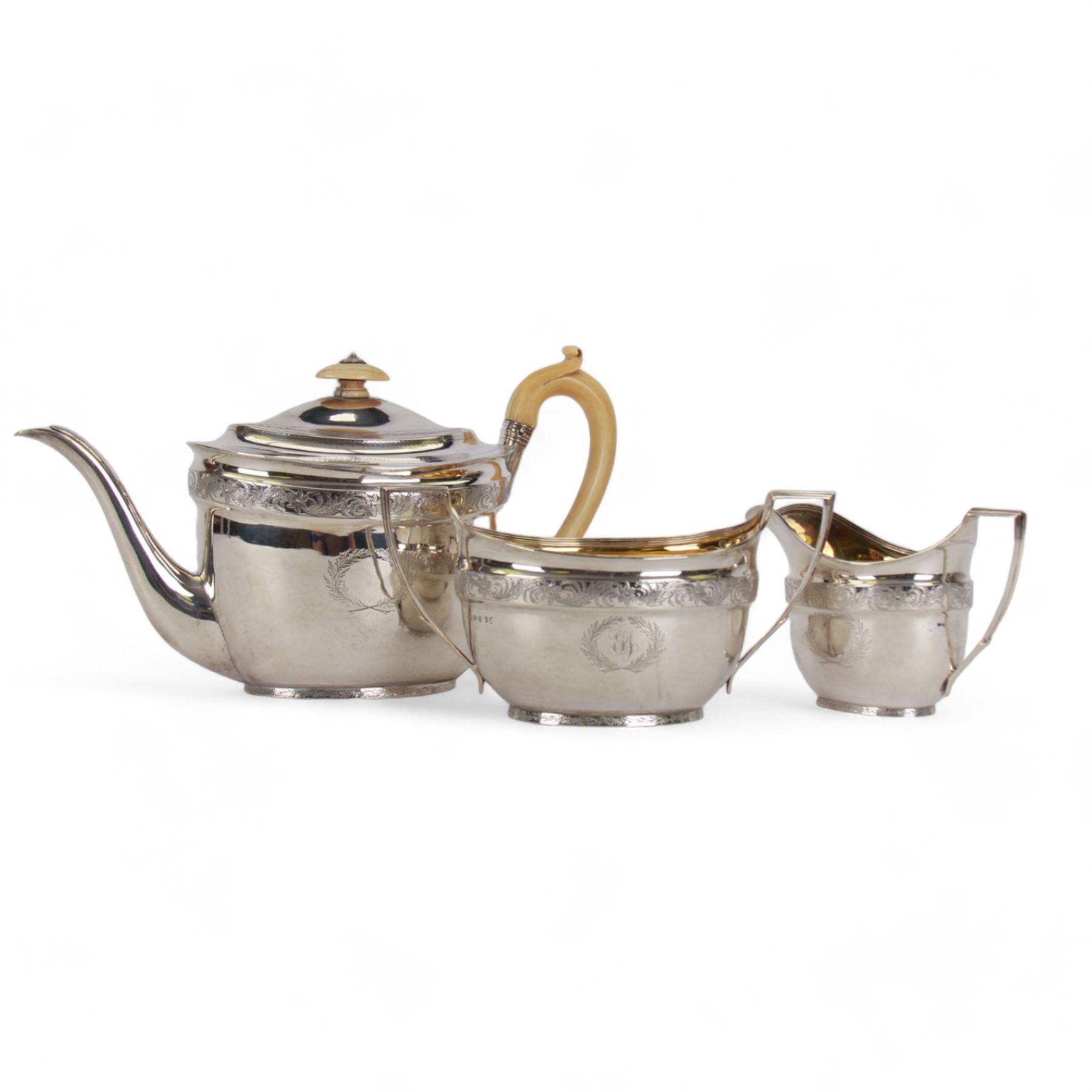 George III silver three piece tea service, comprising teapot with ivory scroll capped curved handle and ivory finial to the hinged cover, twin handled open sucrier with gilt interior, and cream jug with gilt interior, each of oval form with rounded sides, the bodies engraved with central monogram within a seaweed wreath, between engraved foliate bands, hallmarked John Emes, London 1801, teapot including handle H17cm

This item has been registered for sale under Section 10 of the APHA Ivory Act