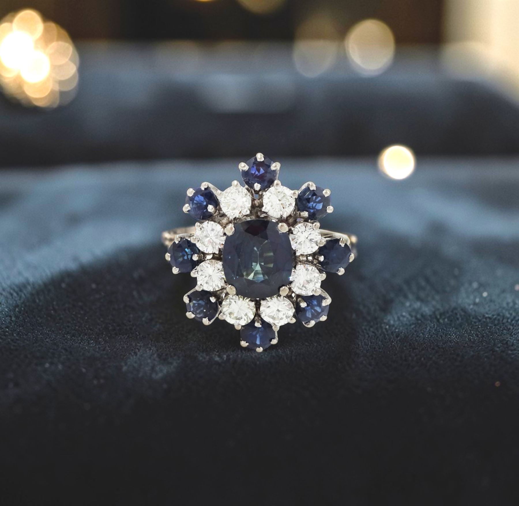 18ct white gold sapphire and diamond cluster ring, single oval cut sapphire of approx 1.85 carat, surrounded by eight round brilliant cut diamonds and eight round cut sapphires, stamped Graff, total sapphire weight approx 3.40 carat, total diamond weight approx 1.35 carat