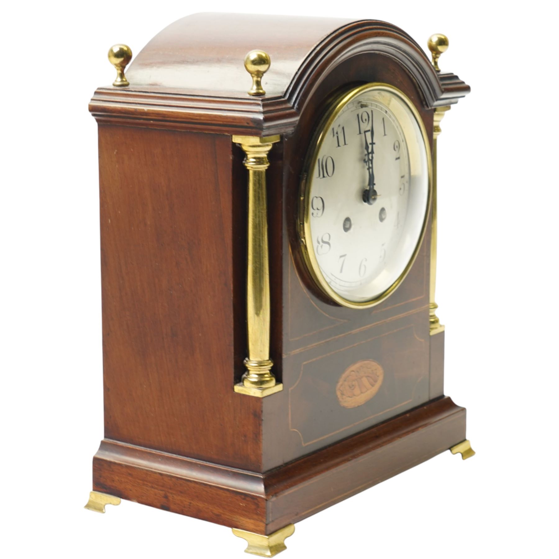 Edwardian-French mahogany cased mantle clock c1910 in a break-arch case with brass finials and recessed brass columns, with inlaid satinwood stringing and conche inlay to the front, raised on a short plinth with bracket feet, twin train movement with rack striking, sounding the hours and half-hours on a coiled gong.
With pendulum and key.