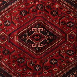 South West Persian Qashqai hand-knotted rug, madder red field with a large stepped diamond medallion with scattered geometric devices and indigo spandrels filled with geometric motifs, framed by multiple narrow guard borders and broad main border, wool fringe ends 