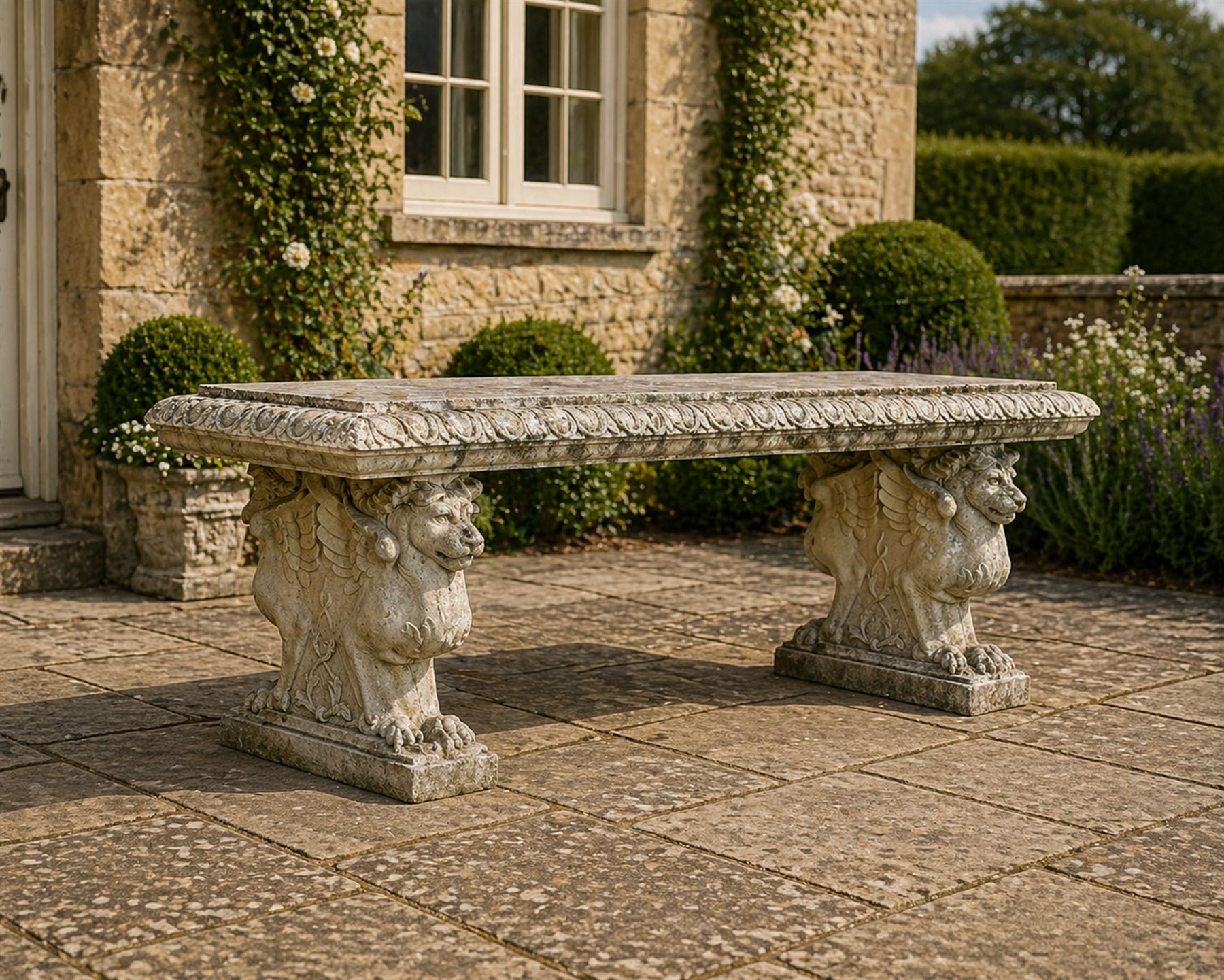 Ornate weathered cast stone rectangular garden bench, raised on winged griffin supports, square plinth bases