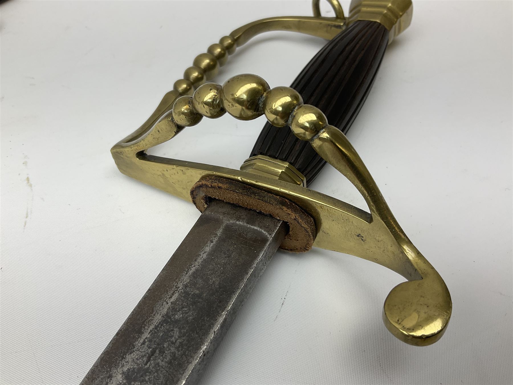 Five-ball spadroon sword with 78.5cm fullered steel blade and brass hilt with fluted swollen grip; in brass mounted leather scabbard, the locket with traces of the makers name John Knubley 11 Charing Cross L97.5cm overall