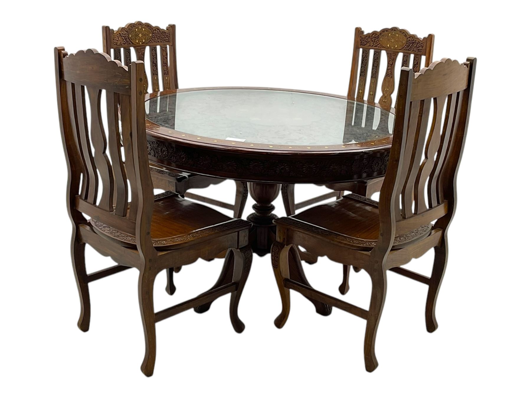 Pakistan carved hardwood brass inlaid circular dining table, and four rail back chairs with saddle seats