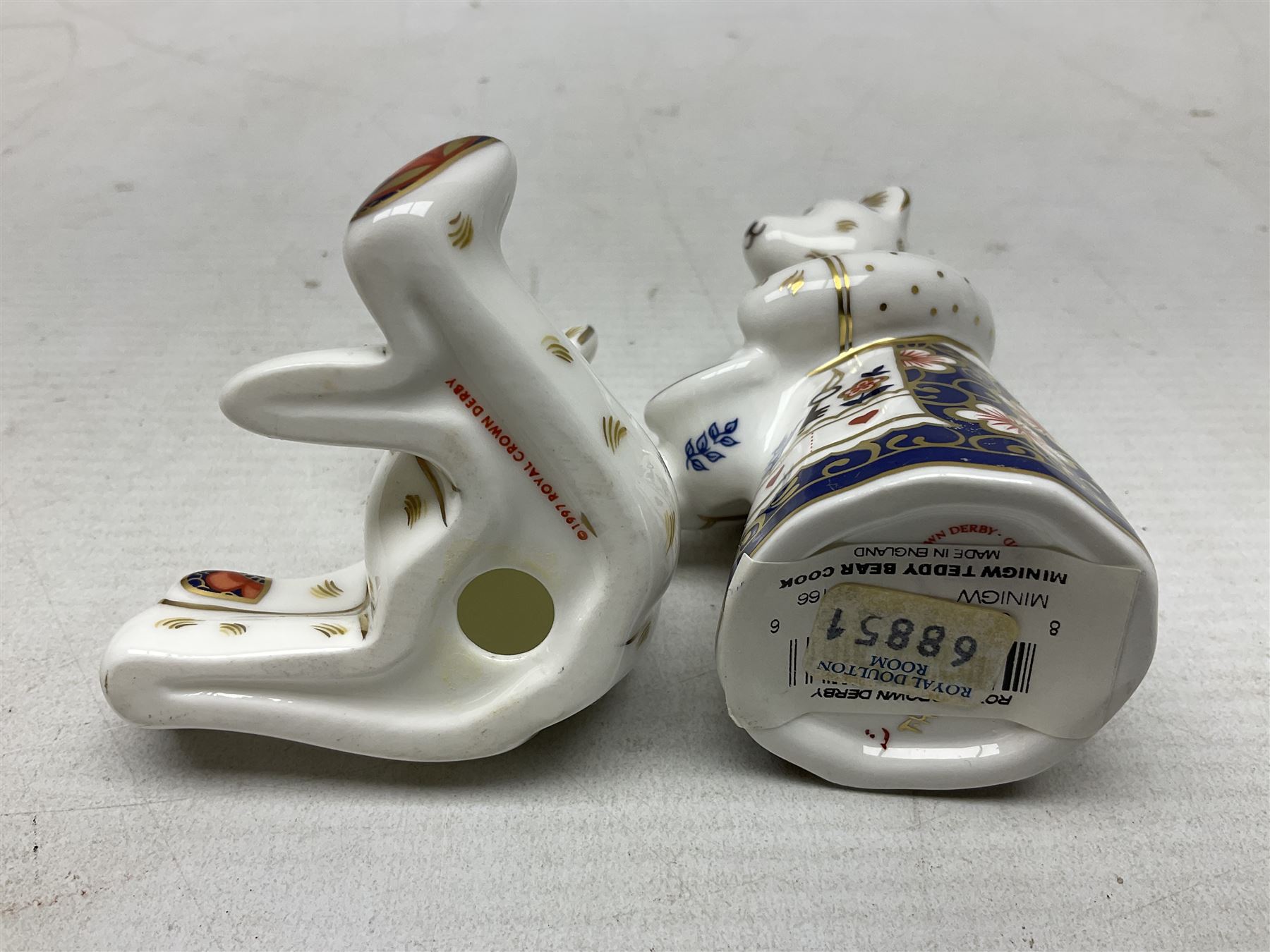 Four Royal Crown Derby teddy paperweights, comprising Teddy Cook, two Teddy George and Seated Teddy, all without stoppers, together with Crown Namestake with gold stopper 