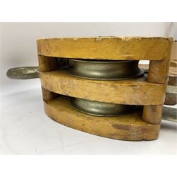 Three ship pulleys comprising wooden block double with swivel eye marked 'wooden block 240mm double rope: 22mm',  wooden block double with upset shackle and wooden block with stiff swivel hook, largest example L50cm