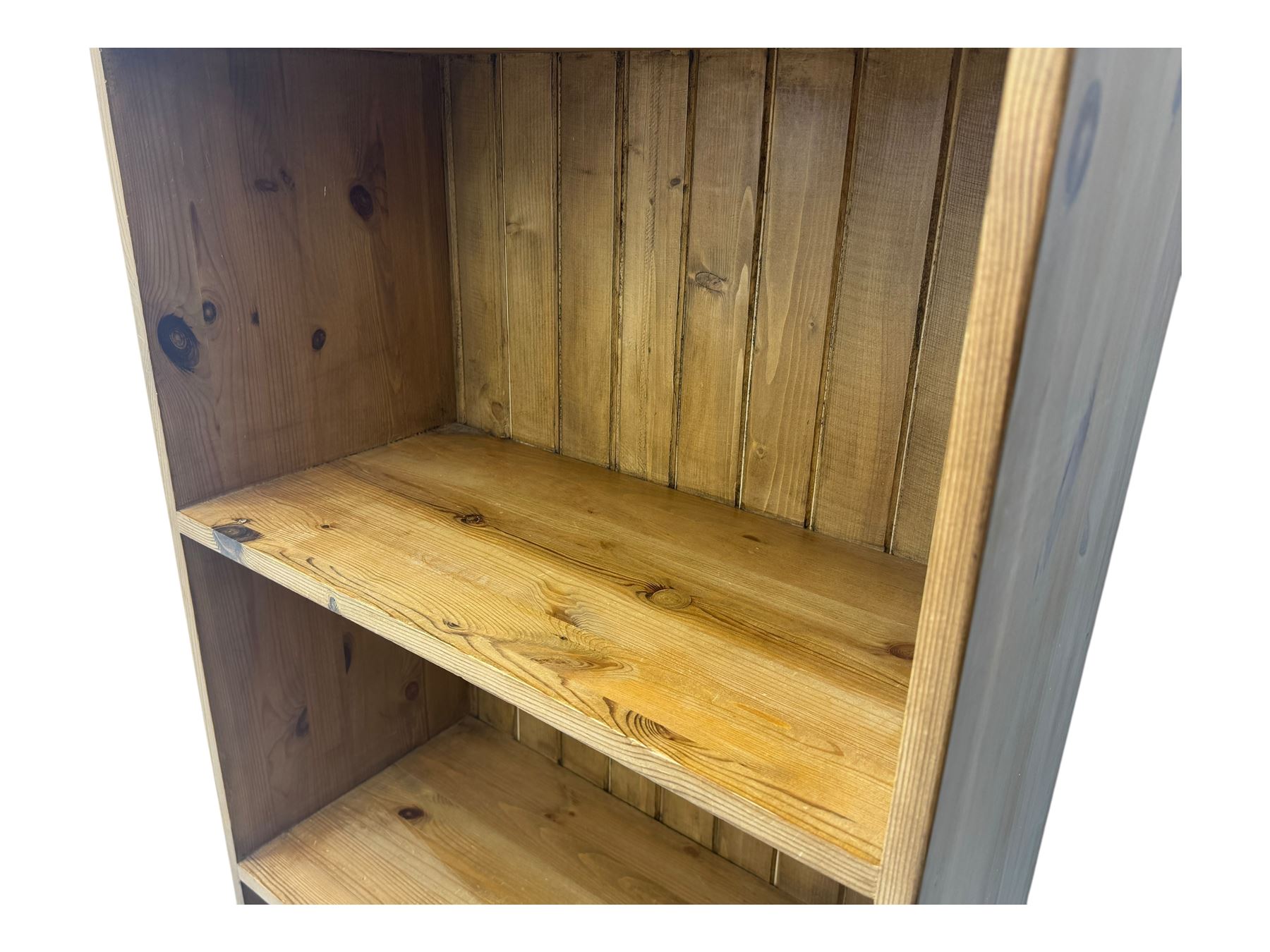 Early 20th century pine bookcase, projecting cornice over arched open shelving area with four fixed shelves, on shaped plinth base