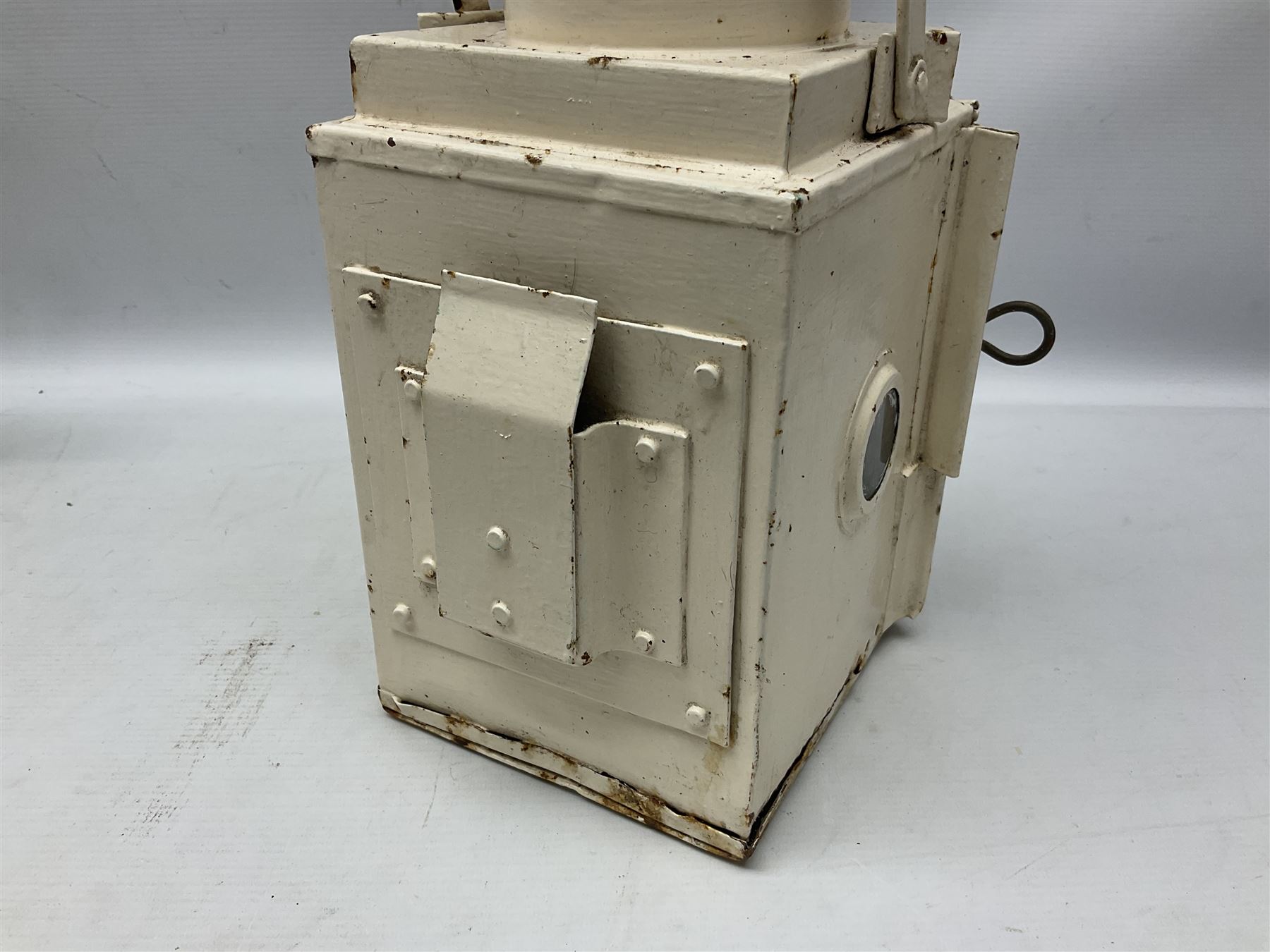 White painted railway lamp, the hinged door with red bullseye glass lens, with tall swing carrying handle, H52cm incl handle