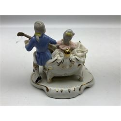 Dresden figure group, modelled as a man playing an instrument to a woman in a lace crinoline dress, upon a gilt rococo decorated base, together with a Dresden style figure group, modeled as a man playing the cello to a woman in a pink lace crinoline dress, tallest example H18.5cm 