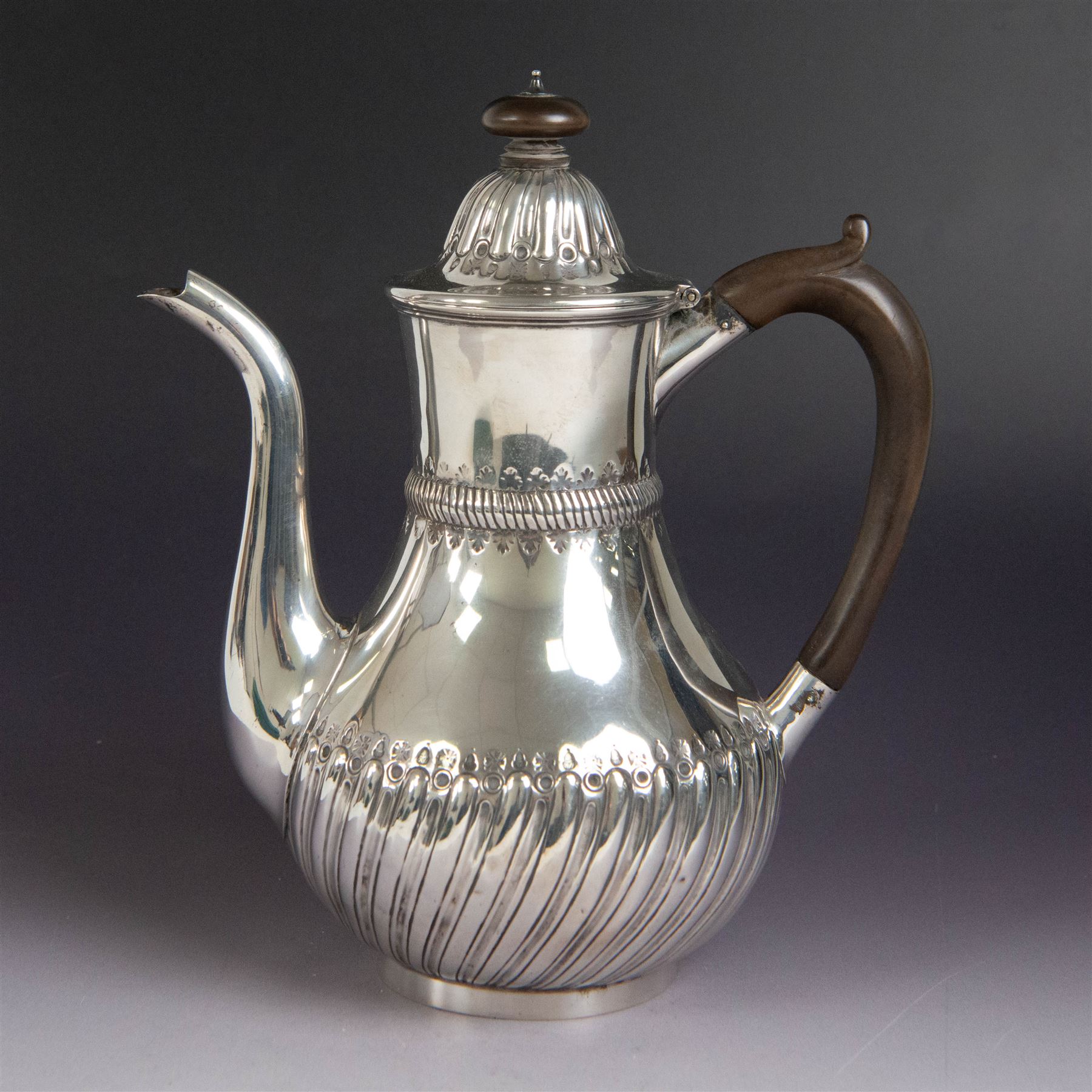 Victorian silver coffee pot, of part fluted baluster form, with central oval cartouche engraved with peryton crest, bordered by C scrolls and chased scales, with impressed acorns, stars and leaves throughout, with wooden handle and finial to domed hinged cover, hallmarked Charles Stuart Harris, London 1883, H23cm