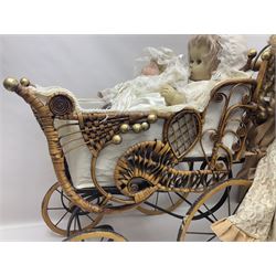Two decorative wicker dolls prams, one with lace parasol,  and eleven dolls, including Leonardo Collection porcelain dolls, tallest pram including parasol H105cm