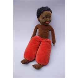  Norah Wellings style black doll, the pressed felt head with inset glass eyes and painted open mouth with teeth, brown velveteen body and red trousers H34cm  