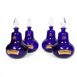 Set of four 20th century Royal Pharmaceutical Society blue glass bottles, of bellied form with clear cut glass spire stopper, each body bearing gilt label in Latin: VIN:ACET:, VIN:ANTIM:, VIN:XERIC:, and VIN:FERR:, and gilt Royal Pharmaceutical Society crest to neck, H25cm

Provenance: From the collection of the family of Peter Green, a practising pharmacist whose career spanned the mid to late 20th century. During his professional life he managed pharmacies in Yeovil, Somerset, and later Selles Chemist in Filey, North Yorkshire, before purchasing and running his own business, Peter Green Pharmacy, located in the Market Place, Malton. The bottles were displayed as part of the traditional shop fittings in both the Filey and Malton pharmacies and were retained as part of his collection.